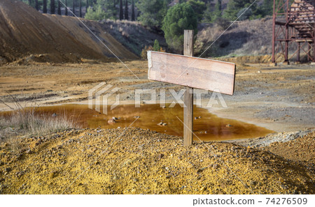 Blank sign on top of chemical waste pile in abandoned mine pit Blank sign on top of chemical waste pile in abandoned mine pit 74276509