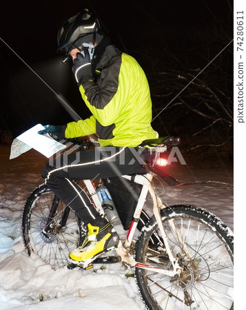 Biker over the map with the race route calling a friend. Extreme racer 74280611