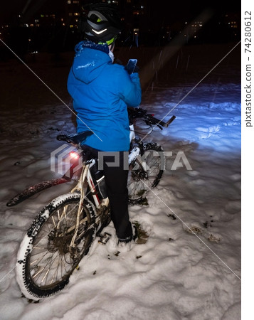 Teenager sit on mtb and takes phone picture of biking in snow Teenager sit on mtb and takes phone picture of biking in snow 74280612