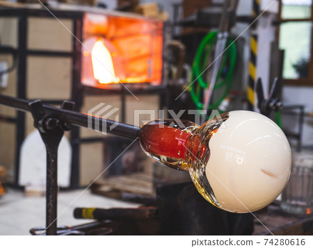 Detail of blowing molten glass into a dish during an art show Detail of blowing molten glass into a dish during an art show 74280616