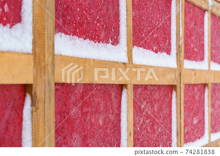 wooden wall in German or Scandinavian style covered snow in winter - the yellow wooden planks is on red wood background, new and clean surface wooden wall in German or Scandinavian style covered snow in winter - the yellow wooden planks is on red wood background, new and clean surface 74281838