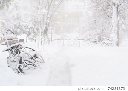 winter city park, benches covered in snow and snowfall winter city park, benches covered in snow and snowfall 74281873