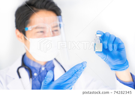 Doctor announcing a vial of vaccine Doctor announcing a vial of vaccine 74282345