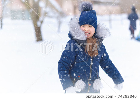 child girl playing with snow in winter outdoor and having fun on snowy winter 74282846