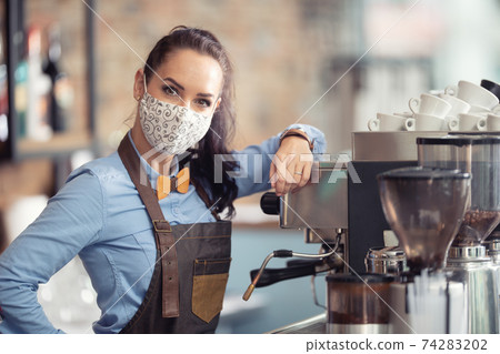 Woman wears protective mask at work, working as a waitress in a coffee house Woman wears protective mask at work, working as a waitress in a coffee house 74283202