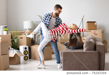 Joyful couple dancing in new apartment 74283304