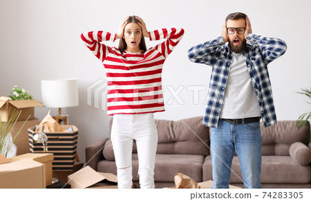 Shocked couple unpacking belongings after relocation 74283305
