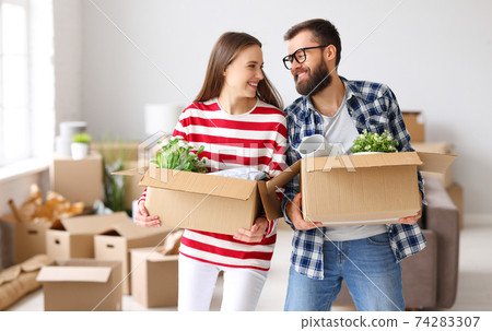 Smiling couple unpacking carton boxes in new home 74283307