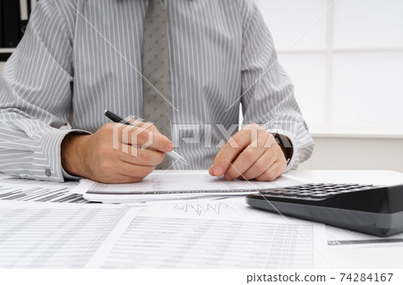 business concept - businessman's working table close view, checks financial reports, writes and counts business concept - businessman's working table close view, checks financial reports, writes and counts 74284167