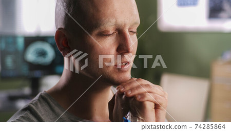 Bald man praying in oncology clinic 74285864