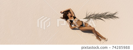 Top Aerial Drone View of Woman in Swimsuit Bikini Relaxing and Sunbathing on Beach 74285988
