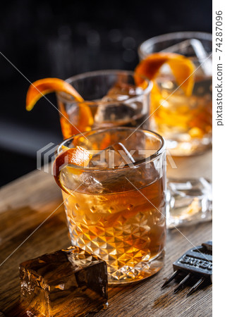 Old fashioned rum cocktail on ice with orange zest garnish 74287096