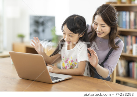 Parent-child video call looking at a computer Parent-child video call looking at a computer 74288298