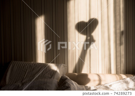 Woman making heart shadow on the wall. World mental health day, hope and love. Valentines 14 February 74289273