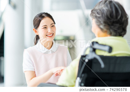Caregiver talking to an elderly person in a wheelchair 74290378