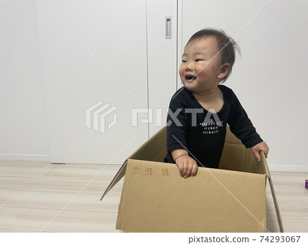 Baby boy playing happily with cardboard Baby boy playing happily with cardboard 74293067