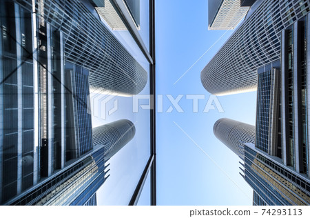 Looking up at the twin towers reflected in the glass in the blue sky 74293113