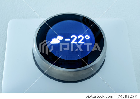 A Smart thermostat showing the outside weather temperature at night during winter. 74293257