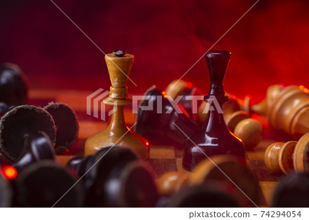 Chess fight, chess pieces on the board, toned in red. Battle fire and smoke Chess fight, chess pieces on the board, toned in red. Battle fire and smoke 74294054