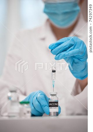 Doctor dials the vaccine into a syringe 74297349