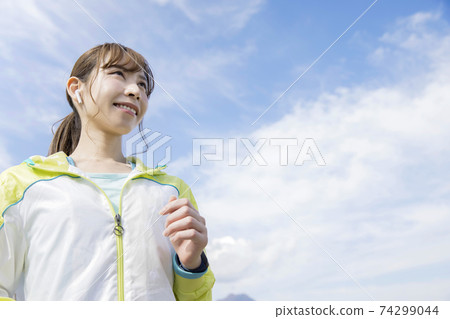 Young woman running with wireless earphones 74299044