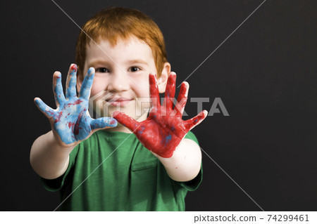 little red-haired boy draws on paper 74299461