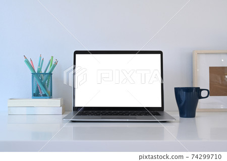 Laptop computer with empty screen, books, coffee cup and stationery on white table. Laptop computer with empty screen, books, coffee cup and stationery on white table. 74299710