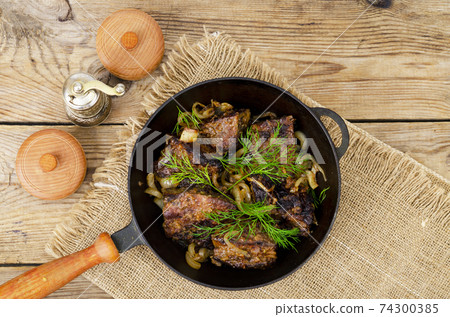Cast-iron frying pan on wooden table with fried liver. Cast-iron frying pan on wooden table with fried liver. 74300385