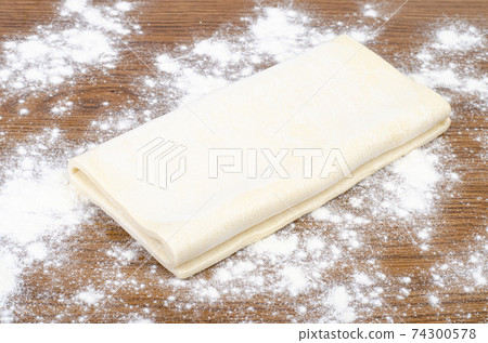 Folded plate of raw dough with flour on wood table. Folded plate of raw dough with flour on wood table. 74300578