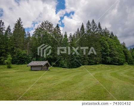 A green meadow with a small wooden barn 74301432