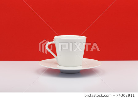 White coffee or tea cup on white table against red background 74302911