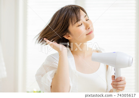 做吹風機的年輕女子 74305617
