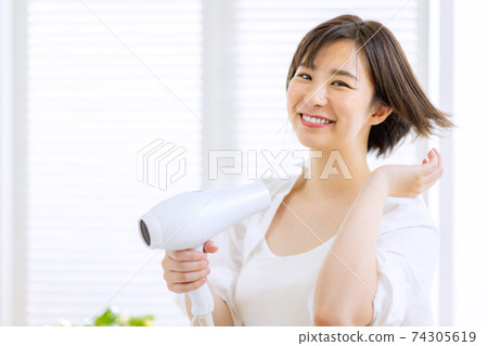 做吹風機的年輕女子 74305619