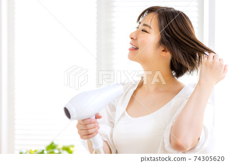 Young woman doing a hair dryer Young woman doing a hair dryer 74305620
