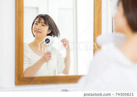 Young woman doing a hair dryer 74305621