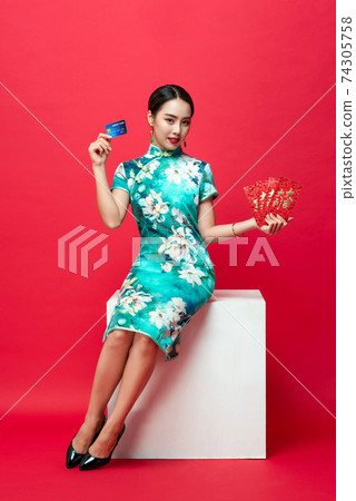 Asian woman in oriental cheongsam presenting red envelope and credit card Asian woman in oriental cheongsam presenting red envelope and credit card 74305758