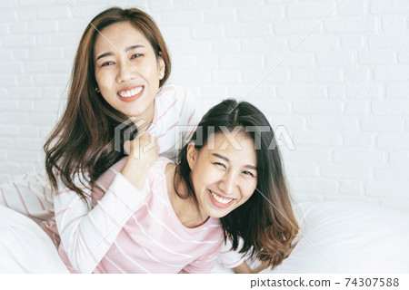 Two pretty best friends forever girlfriend talk, hug and laugh together on bed at cozy home relation Two pretty best friends forever girlfriend talk, hug and laugh together on bed at cozy home relation 74307588
