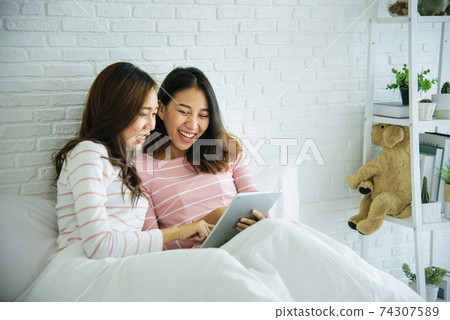 Two pretty best friends forever girlfriend talk, hug and laugh together on bed at cozy home relation Two pretty best friends forever girlfriend talk, hug and laugh together on bed at cozy home relation 74307589