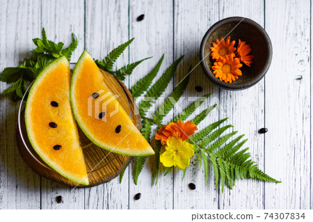 Sweet yellow water melon slices with seeds and flowers, top view Sweet yellow water melon slices with seeds and flowers, top view 74307834
