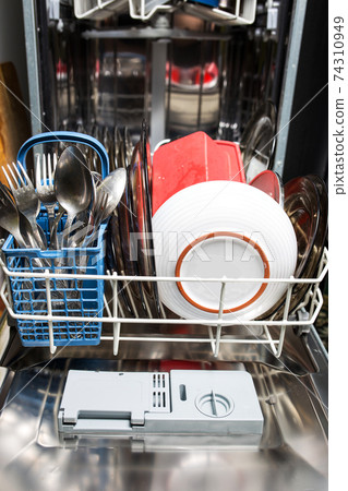 Dishwasher with dirty dishes closeup. Household kitchen appliances. Assistant hostess. Dishwasher with dirty dishes closeup. Household kitchen appliances. Assistant hostess. 74310949