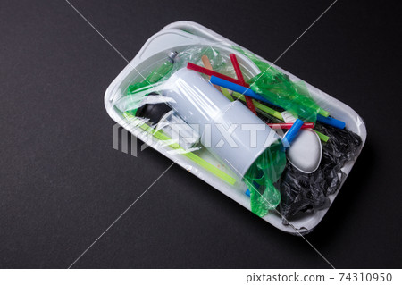 Set of plastic waste in a packed tray on a black isolated background. The problem of ecology and environmental pollution. 74310950