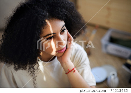 Close-up portrait of sad young woman indoors, resting. 74313485