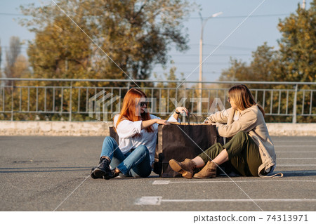 Young women with shopping bags sitting on parking 74313971