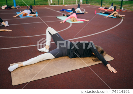 Young fit woman in sportswear trains outdoors on the playground. 74314161
