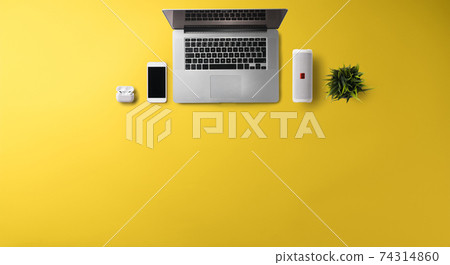 Flat lay top view office desk working space with laptop on yellow background. Copy space. 74314860