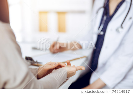 Doctor and patient discussing current health examination while sitting in sunny clinic. Medicine concept 74314917