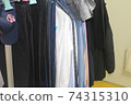 Unorganized clothes hanging on hangers 74315310
