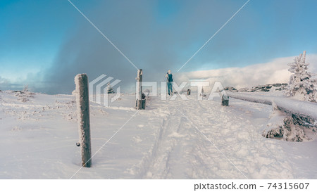 People hiking through a winter landscape in cold and snow 74315607