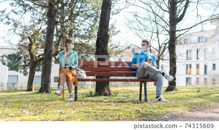 Woman and man with face mask in social distancing flirting 74315609