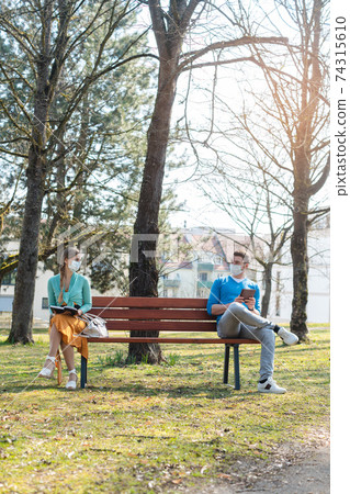 Woman and man with face mask in social distancing flirting 74315610